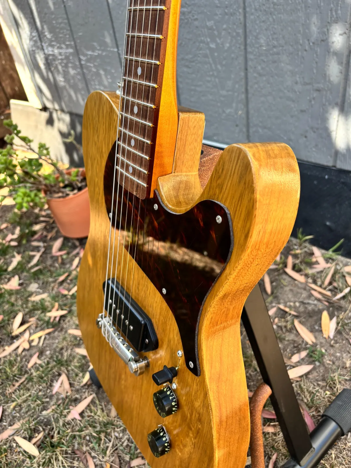 Angled close view of Plume showing body edge, pickguard, neck pocket, and controls.